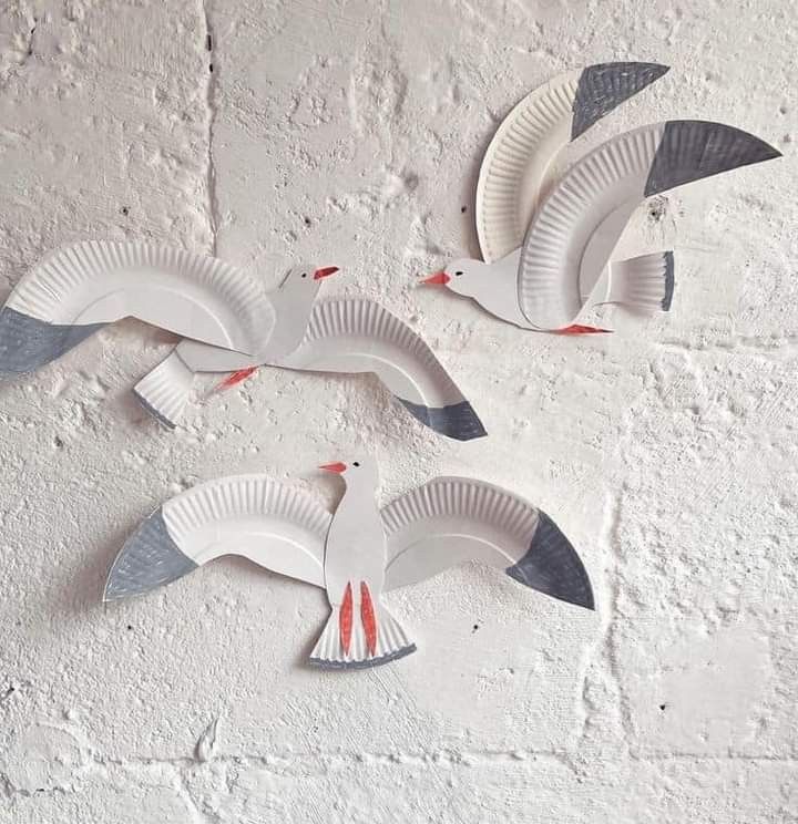 three paper plates shaped like birds flying in the air