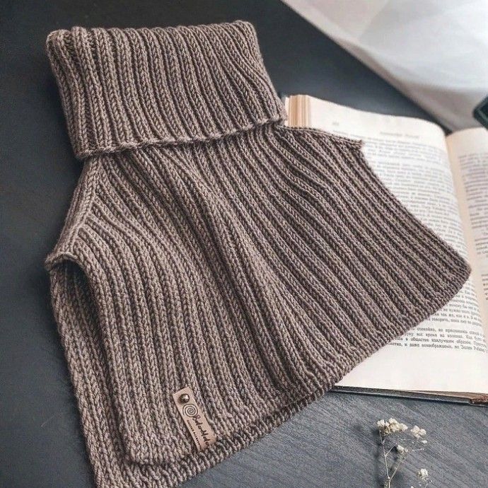 a knitted scarf sitting on top of an open book