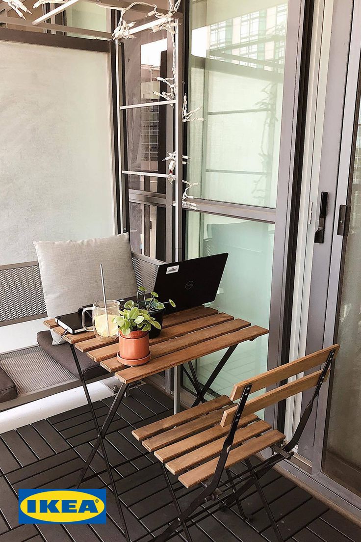 a laptop computer sitting on top of a wooden table next to a chair and window