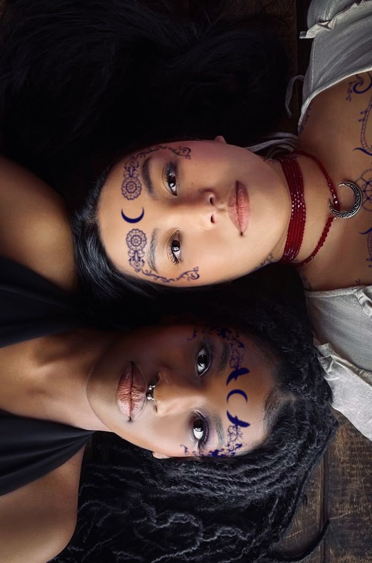 two young women with tattoos on their faces are posing for the camera and looking at the camera