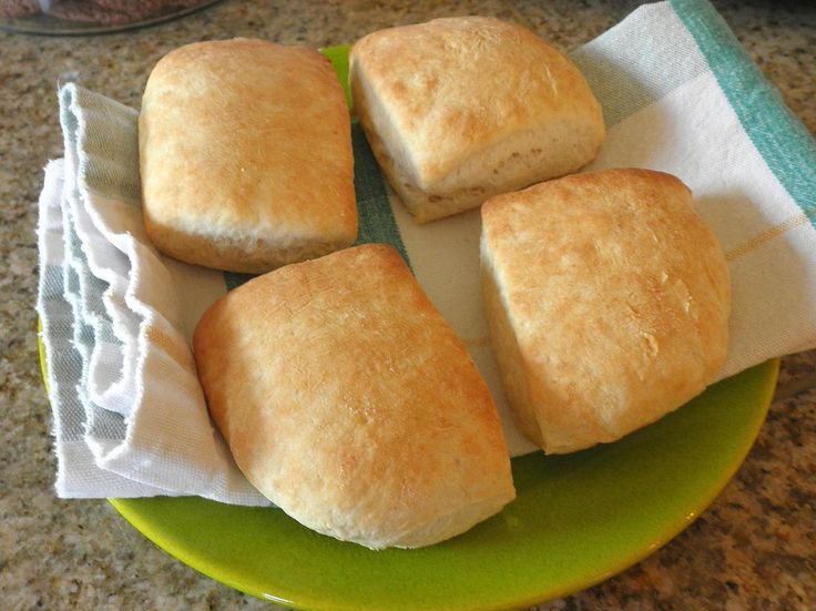 four biscuits sitting on top of a green plate next to a white towel and bowl