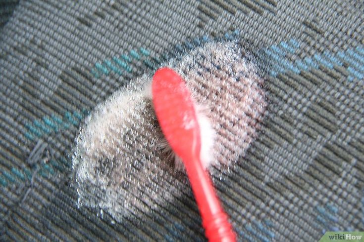 a red toothbrush sitting on top of a gray carpet next to a hole in the floor