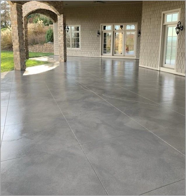 an empty patio in front of a house with glass doors and brick pillars on either side