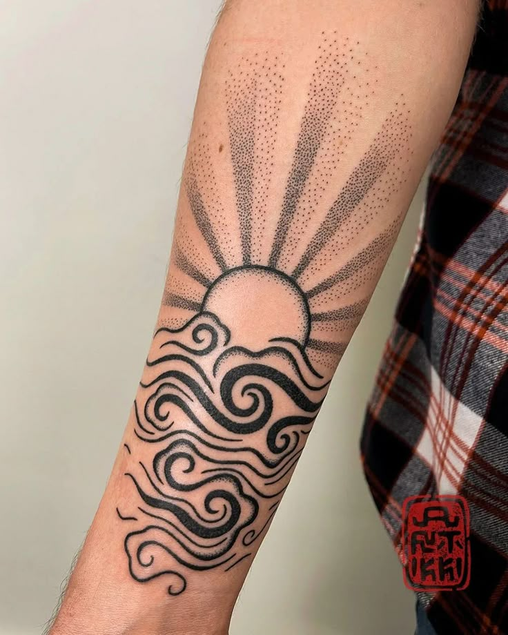 a man's arm with a sun and waves tattoo design on the left forearm