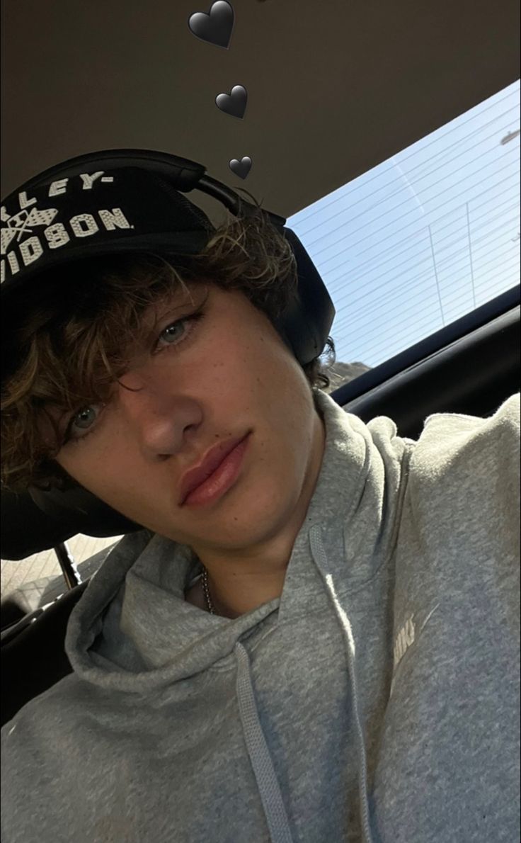 a boy in a car wearing a hat with the word boston on it's side