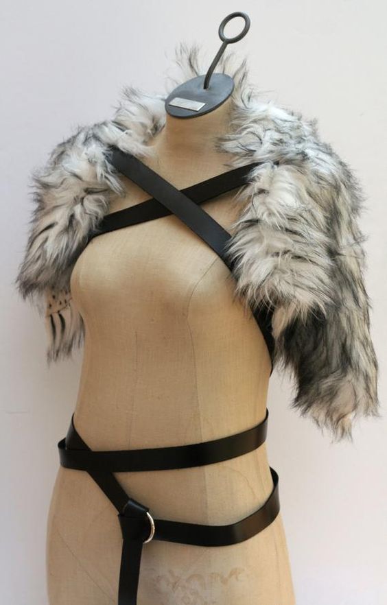 a mannequin wearing a leather harness with fur collar and metal clasps on it