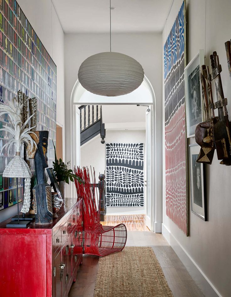 a hallway with red chairs and artwork on the wall, along with an area rug