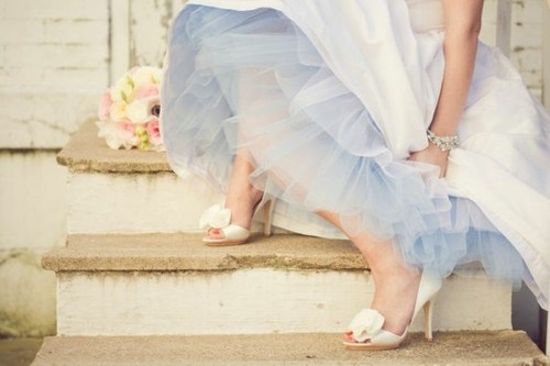 a woman in a blue dress sitting on steps with her feet up and wearing white shoes