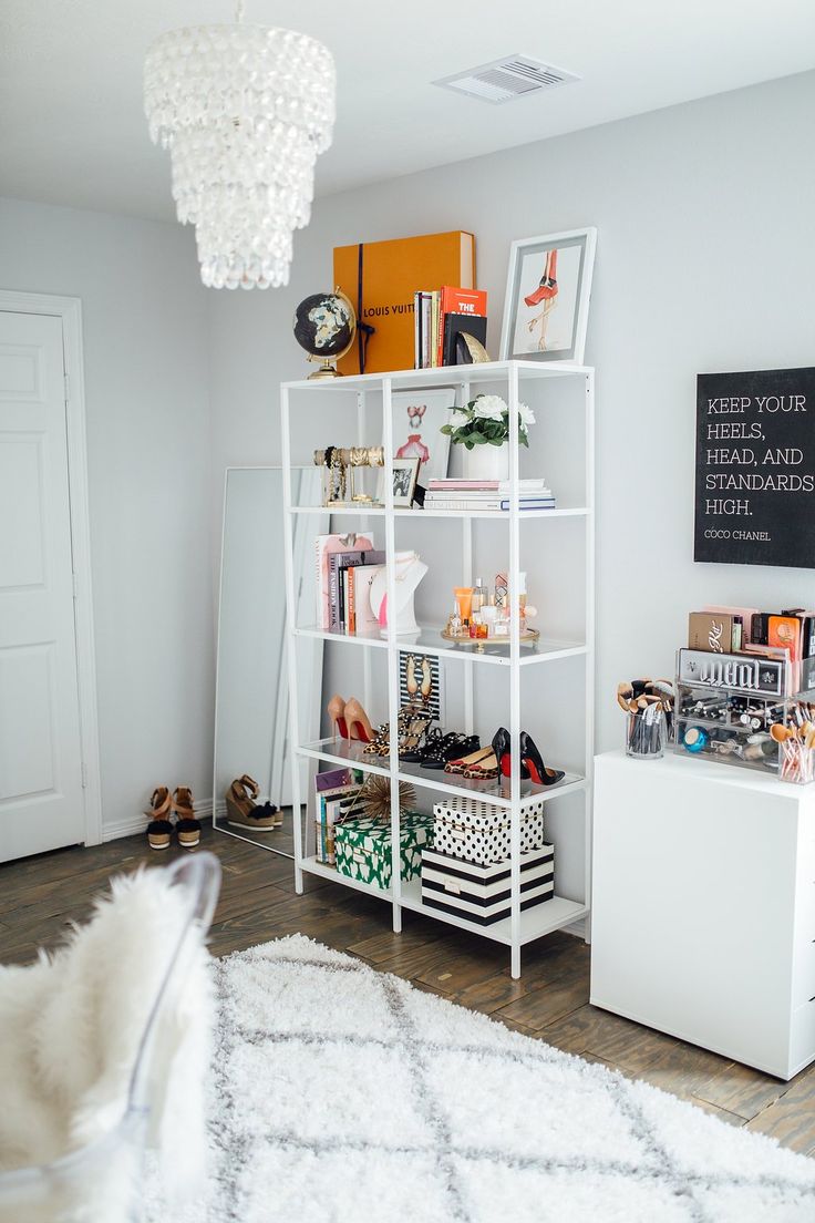 a white book shelf filled with lots of books and other items on top of a hard wood floor