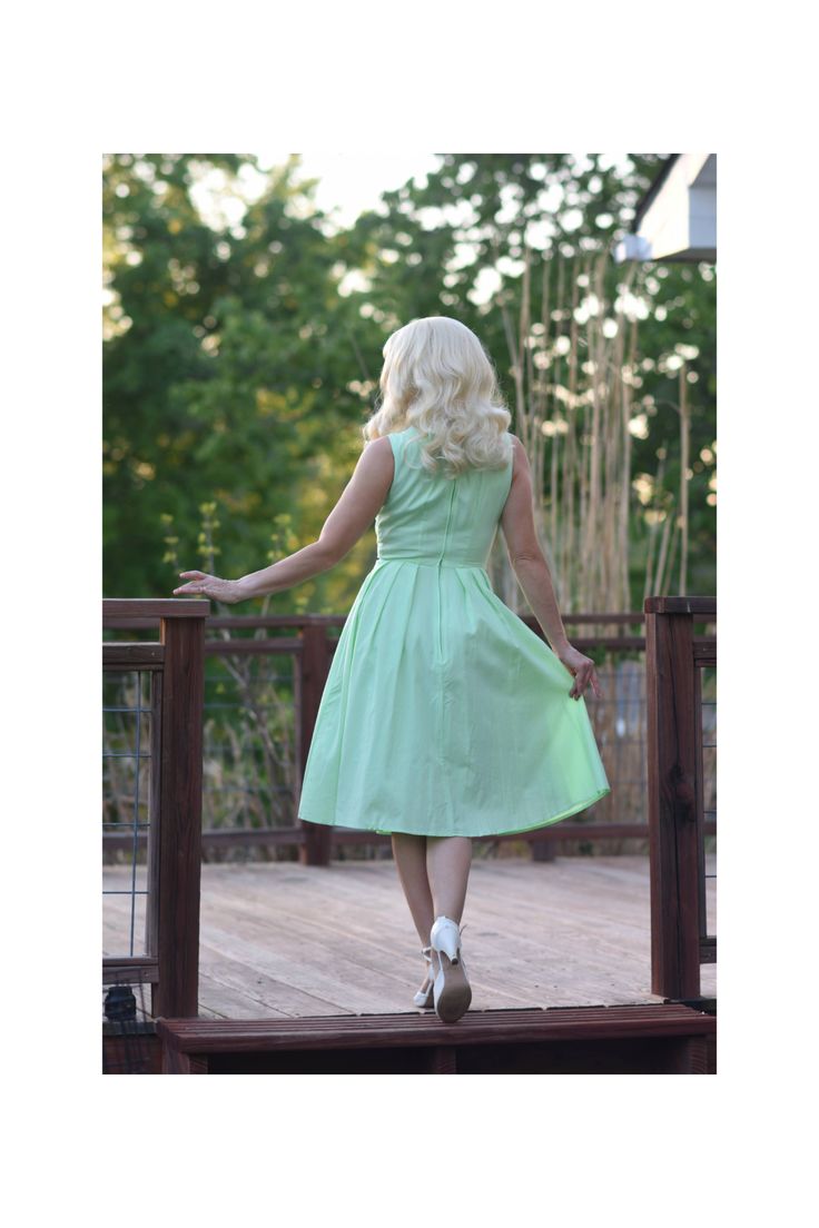 Samantha in Nile Green will add some cheer and positive energy to your wardrobe. Reminiscent of the 1960's color palettes of soft light green with white trim detail on the bow and center front makes this darling dress perfect for casual everyday wear. Features pleated circle skirt with hidden side seam pockets. Don't forget to add a crinoline underneath for that true-to-vintage look! PRODUCT DETAILS: Scoop neckline with bow detail Sleeveless Pleated circle dress Pockets Fabric has no stretch Eas Classic Green Spring Dress, Green Dress With Pleated Waist, Classic Green Cotton Dress, 1950s Style Green A-line Dress, Green Spring Dress With Pleated Hem, Spring Green Dresses With Pleated Hem, Green Dress With Pleated Full Skirt, Green Pleated Hem Dress For Spring, Green Pleated Full Skirt Dress