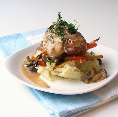 a white plate topped with mashed potatoes and meat covered in mushrooms on top of a blue napkin