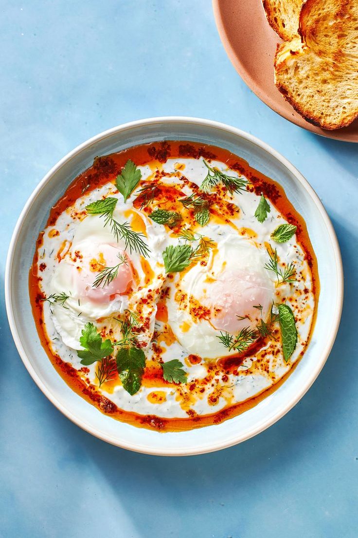 an egg dish in a white bowl on a blue surface with the title, how to make your own glub turkish eggs