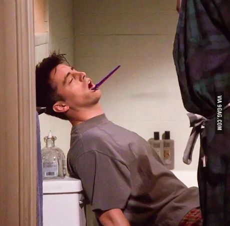 a man laying on the toilet with his mouth open and toothbrush in his mouth