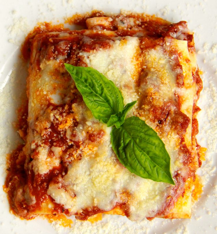 a square piece of lasagna with basil leaves on top