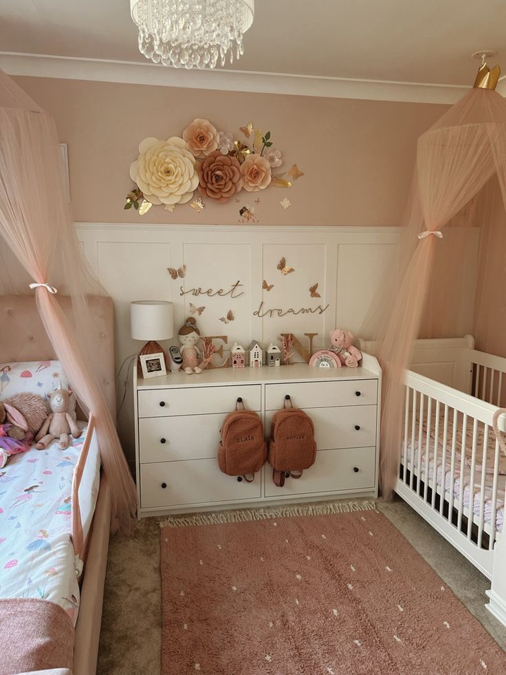 a baby's room with two cribs, a dresser and flowers on the wall