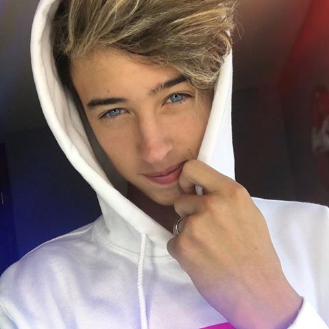 a young man with blonde hair wearing a white hoodie