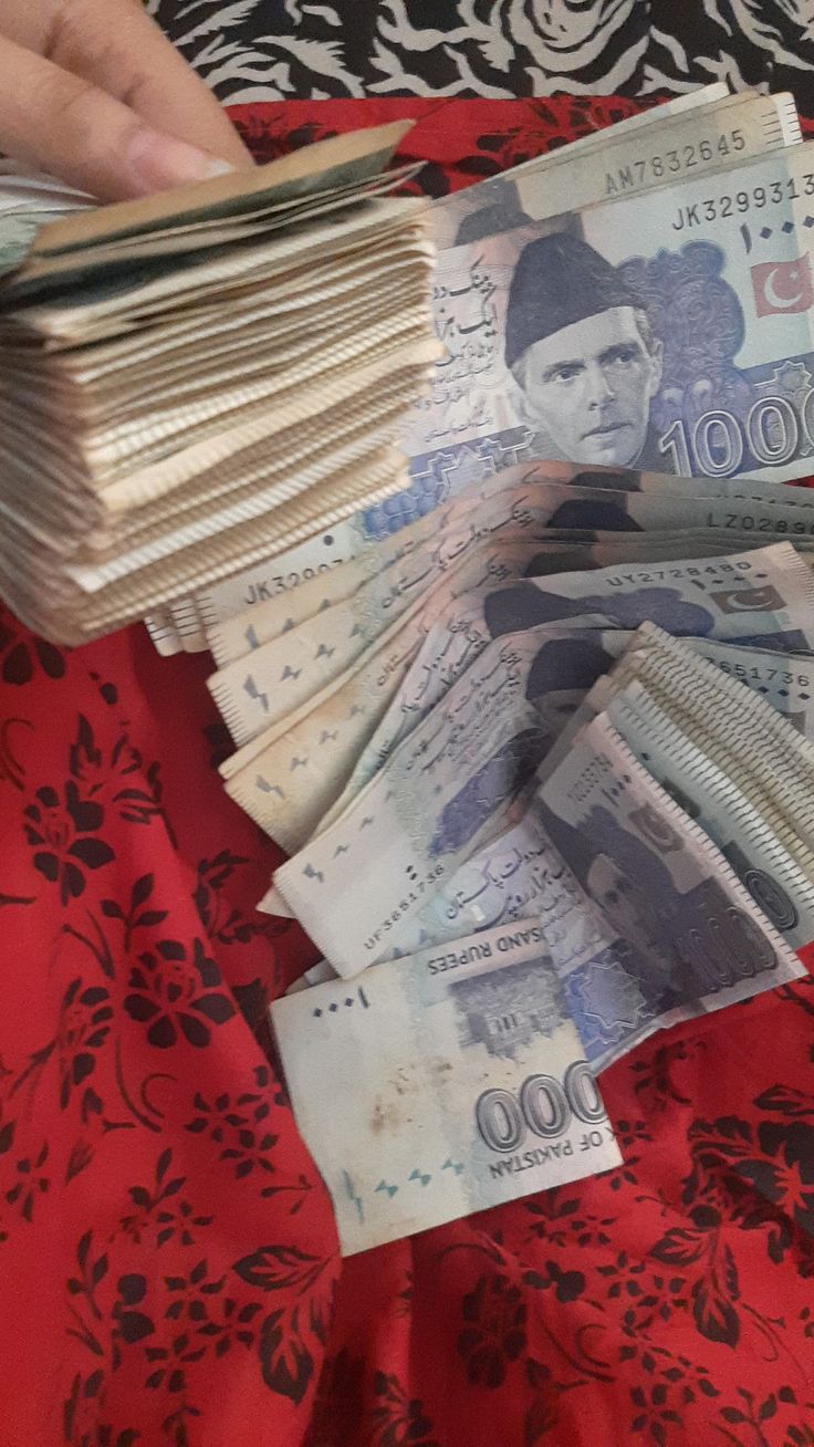 a person is holding stacks of money in their hands on a red and black table cloth