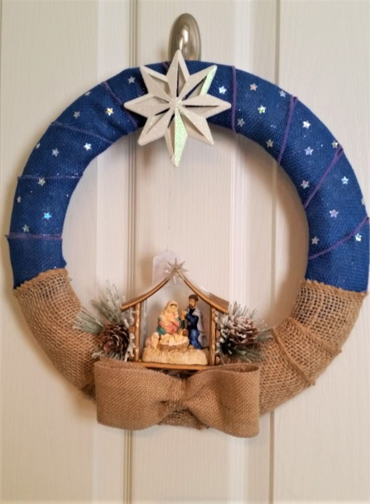 a christmas wreath with a nativity scene hanging from it's front door frame