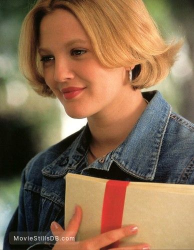 a woman with blonde hair holding a gift box and looking off to the side while smiling