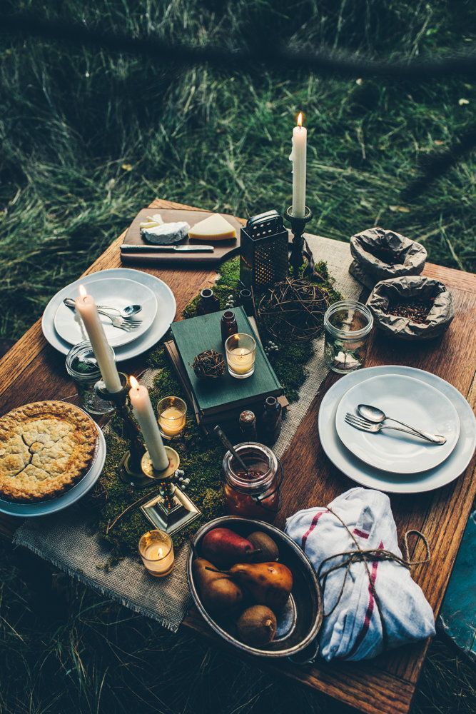 a wooden table topped with plates and candles