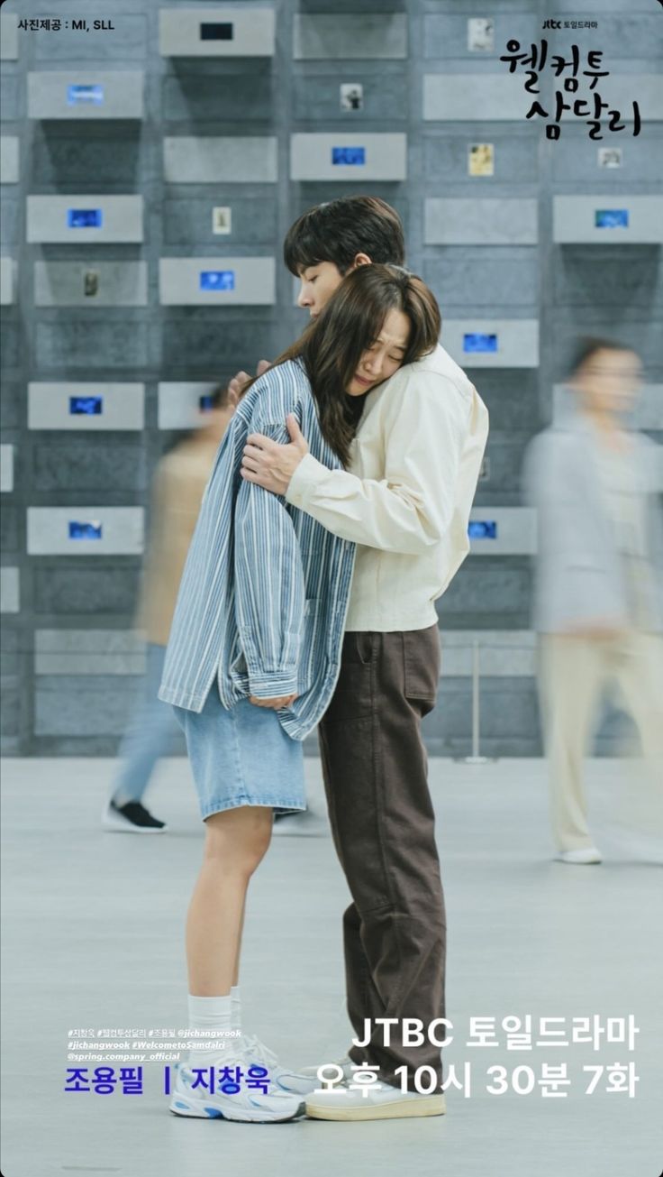 a man and woman embracing each other in front of a wall