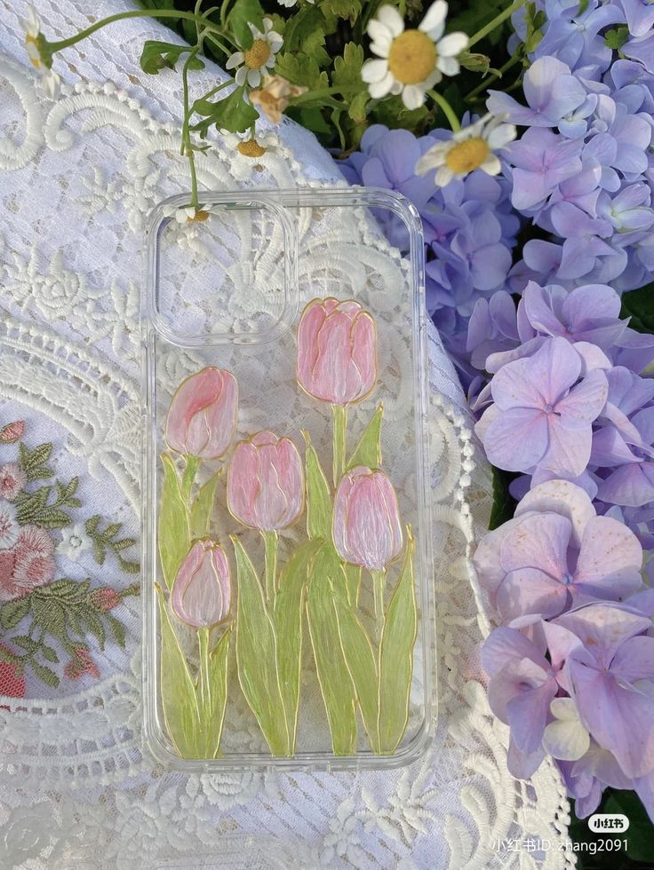 some pink flowers are sitting on a doily next to purple and white flowers with green stems