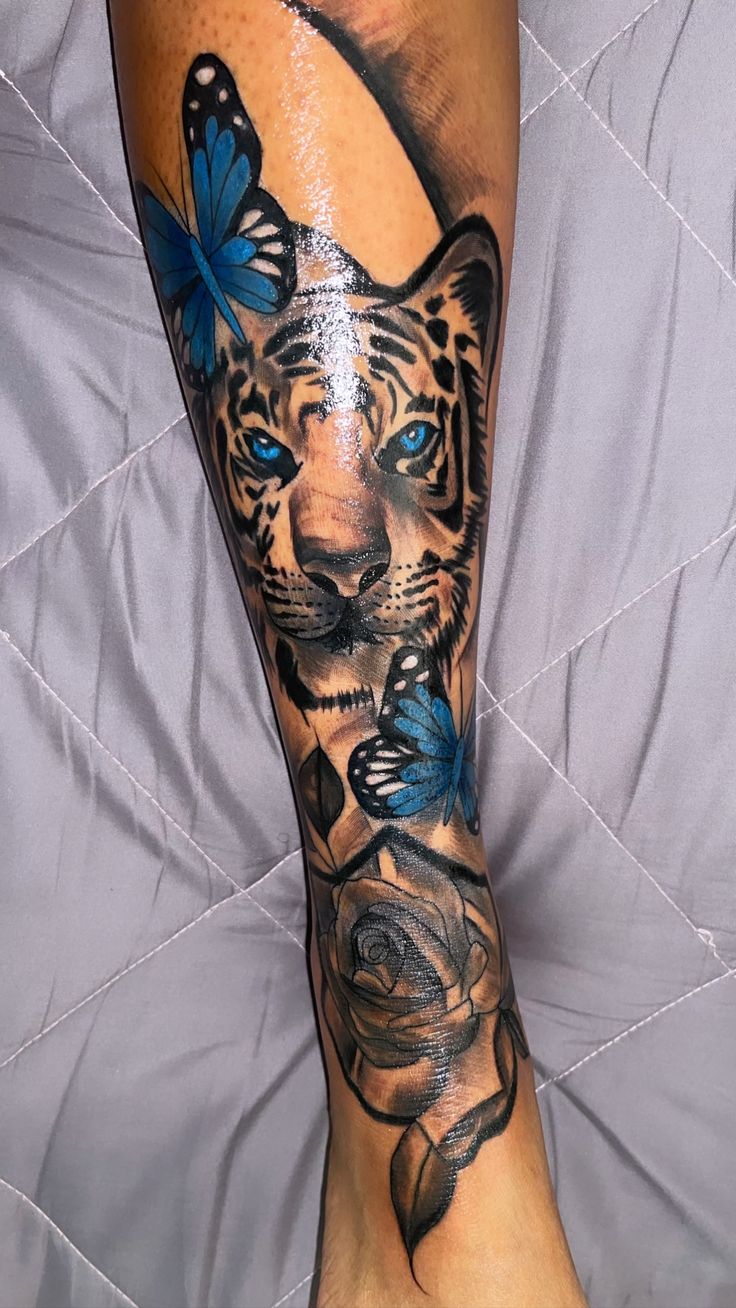 a tiger with blue butterflies on its leg is shown in this tattoo design by person