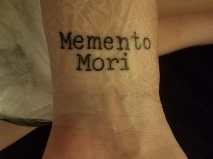 a person with a tattoo on their wrist that says mementoo mori in black ink