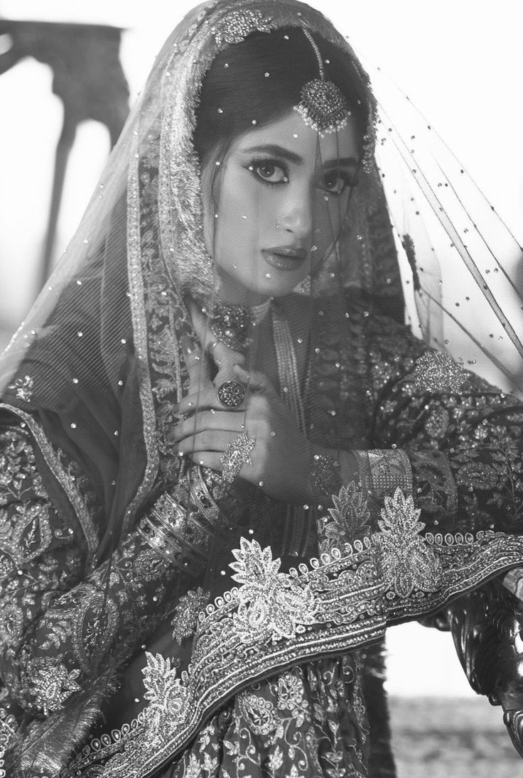 a woman in a red and gold bridal outfit posing for the camera with her hand on her hip