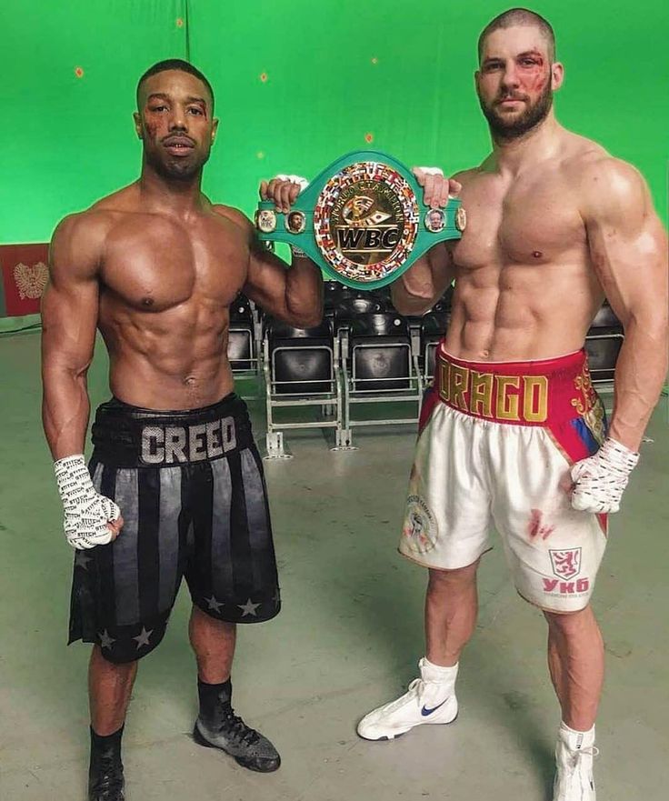 two men standing next to each other in front of a green background holding boxing gloves