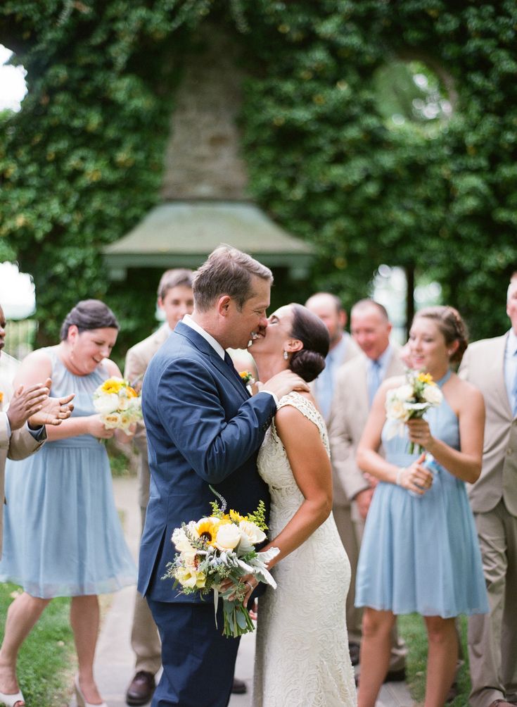 a bride and groom kissing in front of their wedding party