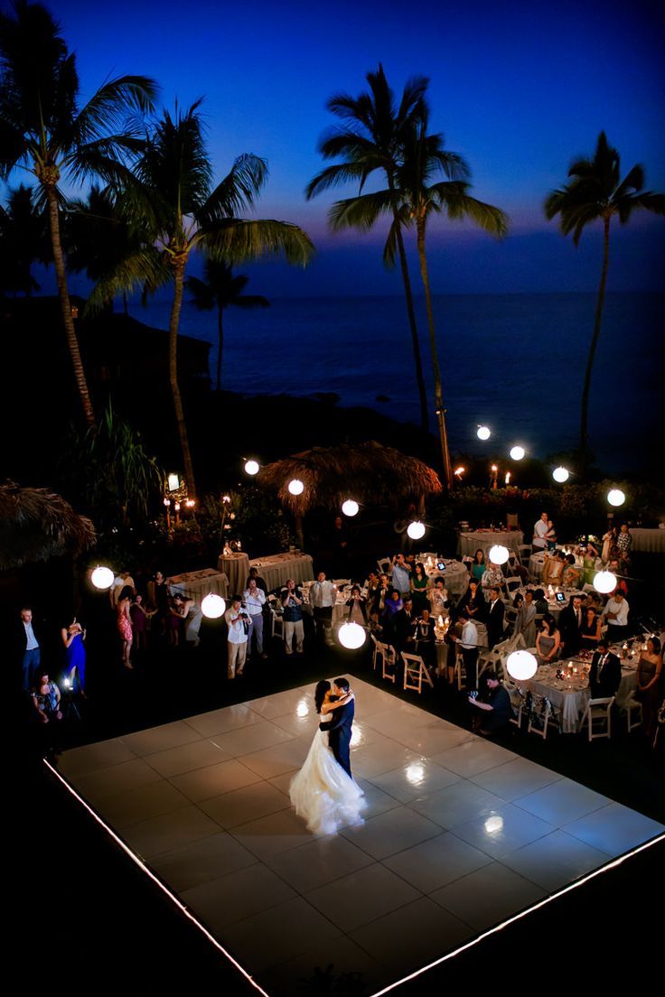 a bride and groom dance on the dance floor at their wedding reception in front of an ocean view