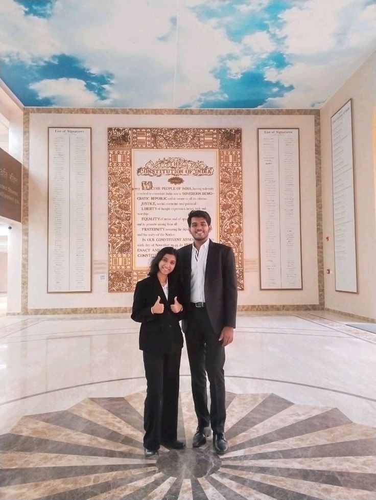 a man and woman standing in front of a wall with clouds painted on the ceiling