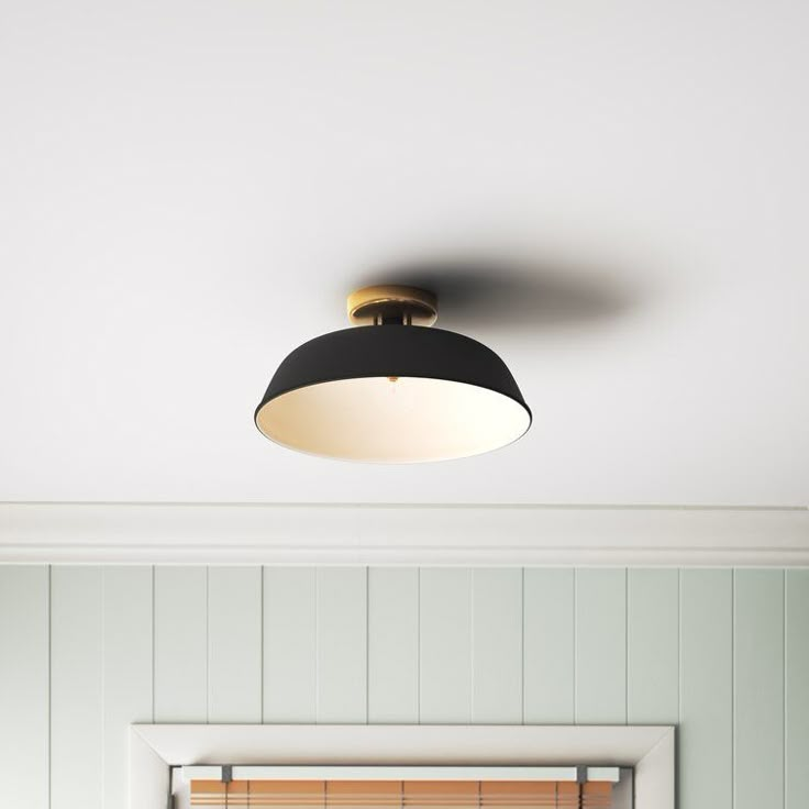 the light is on above the bed in the room with white walls and wood paneling