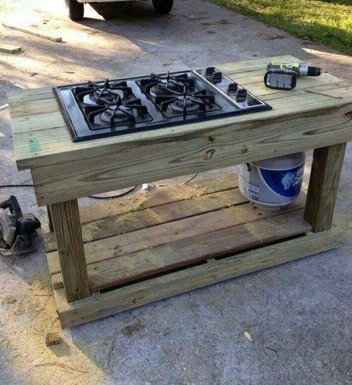 a table made out of pallet wood with a stove top on it and tools next to it