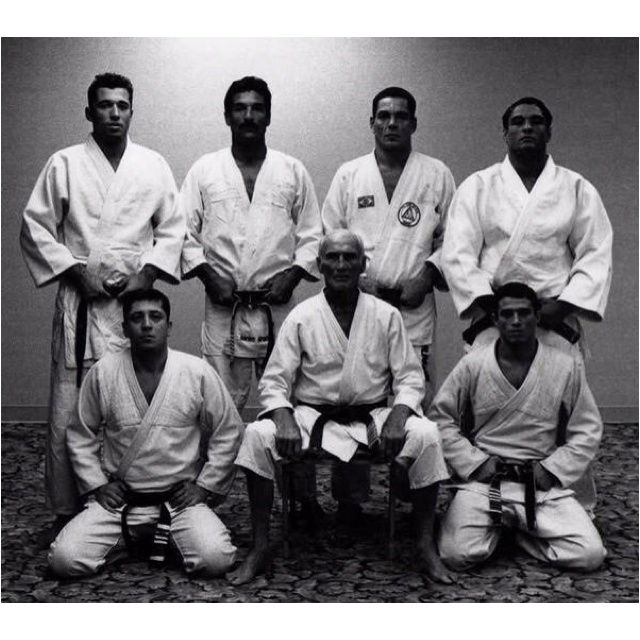 a group of men standing next to each other in front of a wall wearing karate uniforms