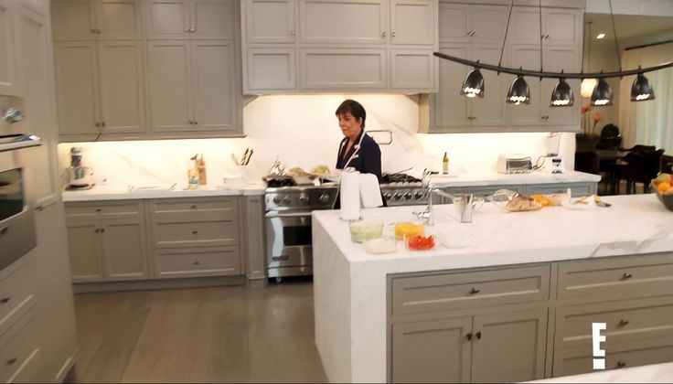 a woman standing in a kitchen preparing food on top of a white countertop next to an oven