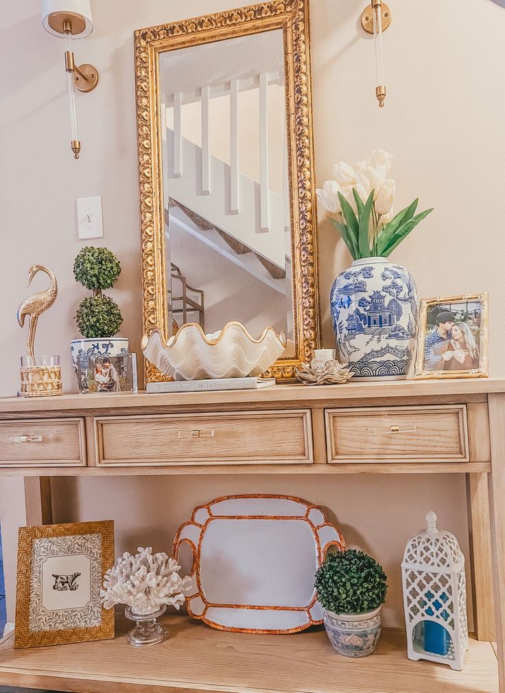 there is a table with vases and pictures on it, along with a mirror