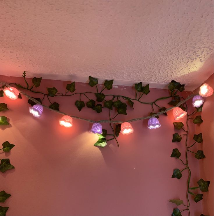 a pink wall with ivy and lights on it