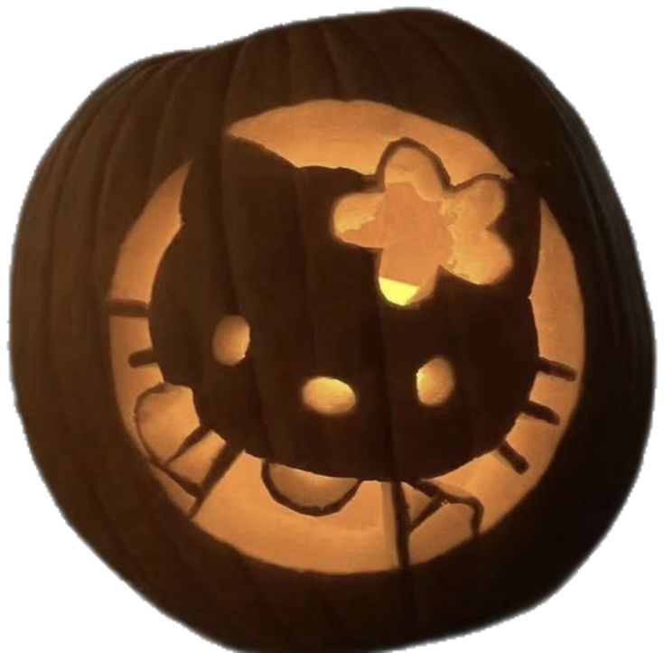 a hello kitty pumpkin with the face cut out and eyes glowing in the night light