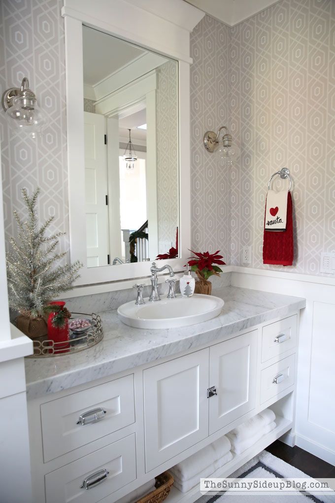 a bathroom with a sink, mirror and christmas decorations on the counter top in front of it