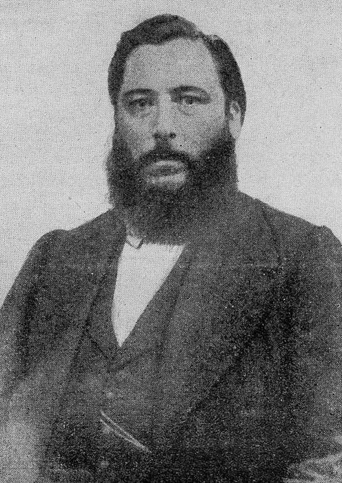 an old black and white photo of a man with a beard wearing a suit jacket