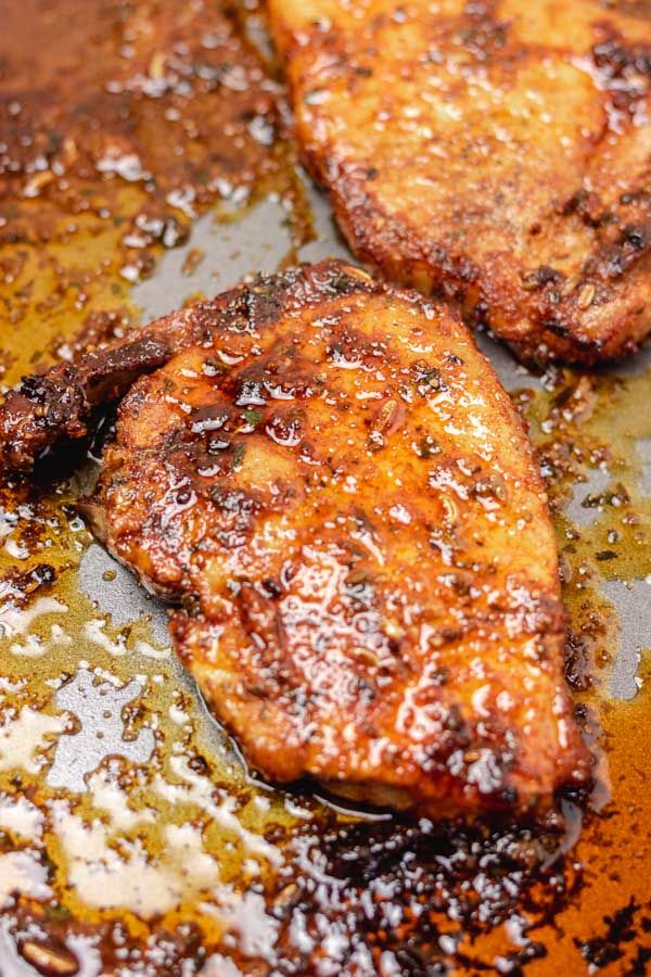 three pieces of meat sitting on top of a pan covered in gravy and seasoning