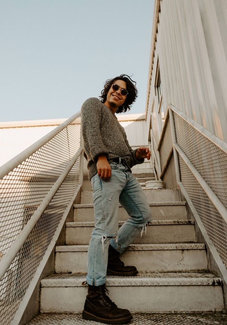 a man is standing on the stairs talking on his cell phone while wearing jeans and a sweater