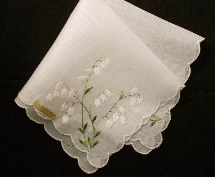 two napkins with white flowers on them sitting next to each other in front of a black background