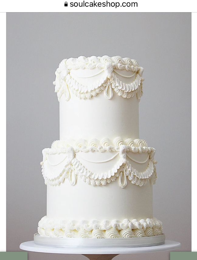 a three tiered white wedding cake sitting on top of a table