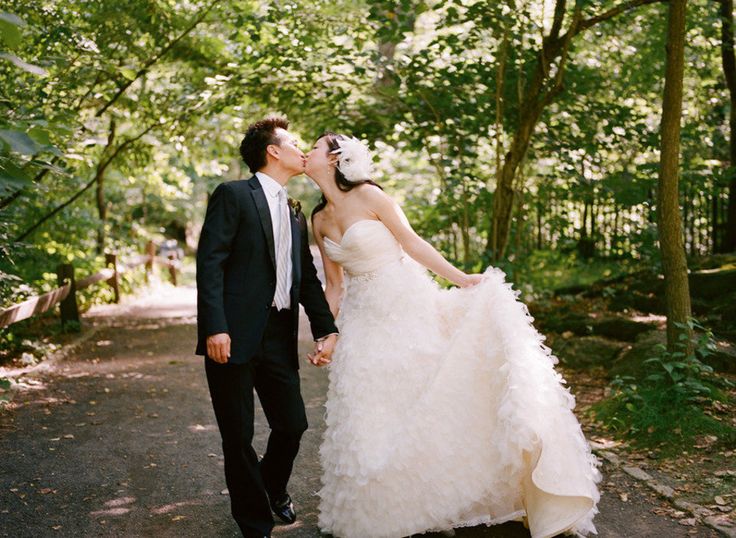 a bride and groom kissing in the woods