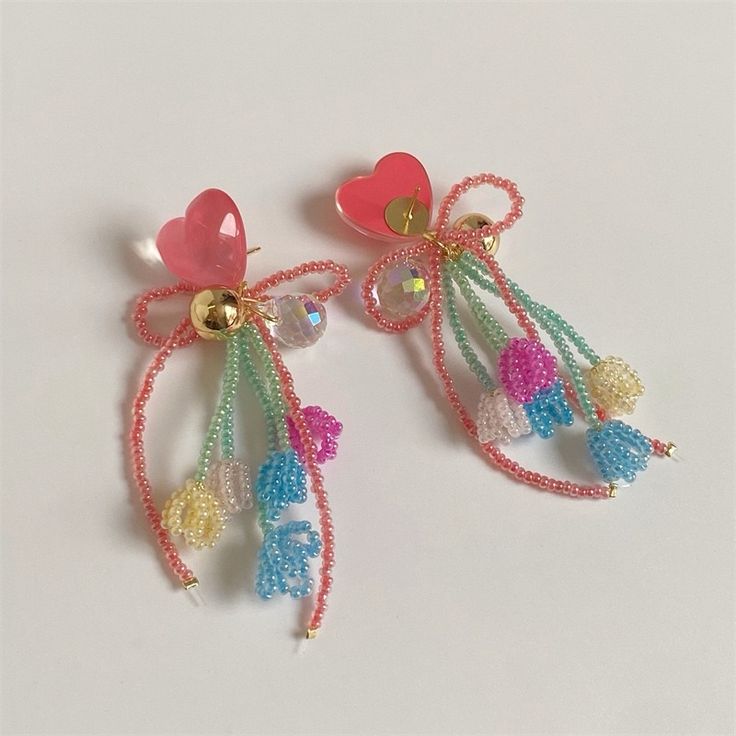 two pairs of colorful beaded earrings with hearts and bells hanging from the earwires