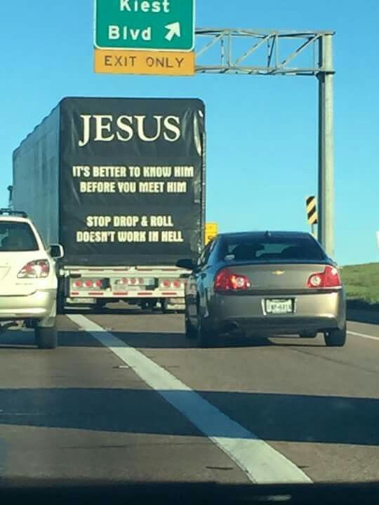 a truck driving down the road with a jesus sign on it's back end