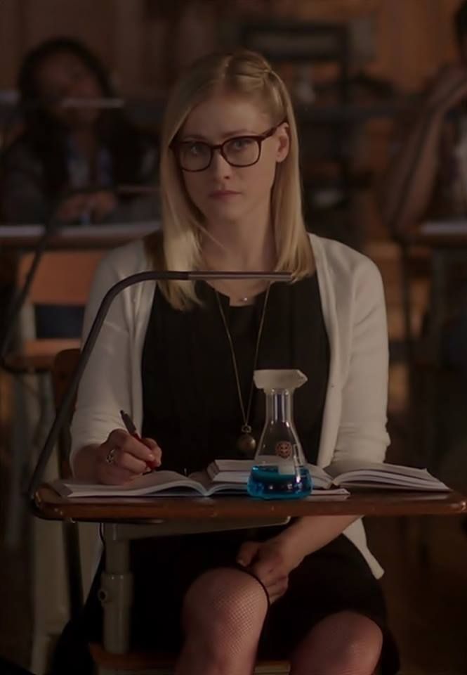 a woman sitting at a table with a book and beakle on her lap top